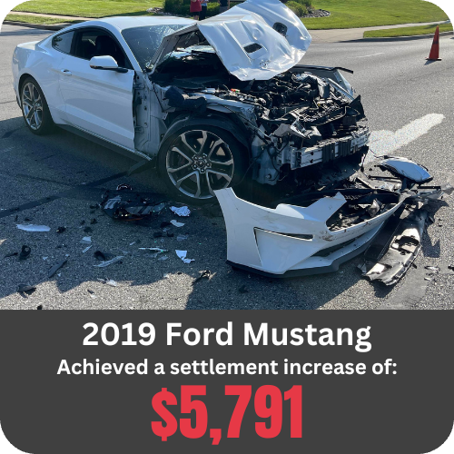 2019 Ford Mustang with severe front-end crash damage on a city street.