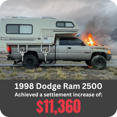 1998 Dodge Ram 2500 pickup truck with Bigfoot camper on fire near the hood, parked on the Interstate I-15 in Utah